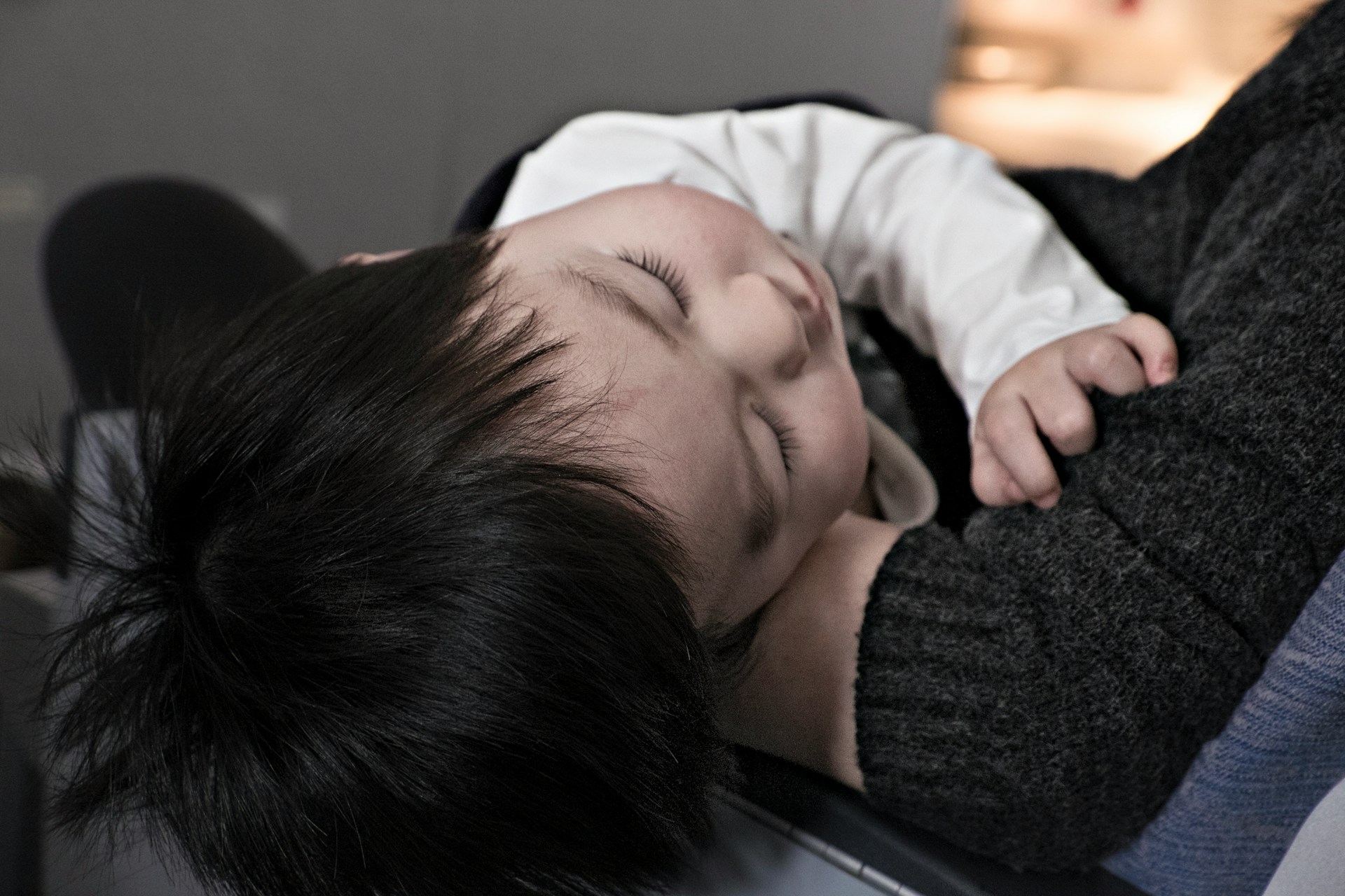 Criança adormecida em paz contra o peito do progenitor — ilustra a abordagem de naturopatia integrativa para sono infantil